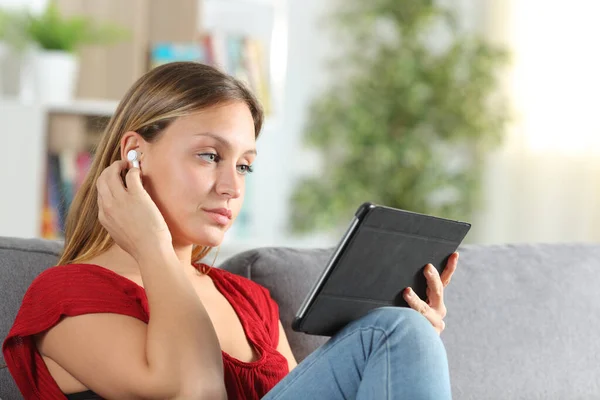 Wanita Serius Mendengarkan Musik Dengan Earbuds Atas Tablet Duduk Sofa — Stok Foto