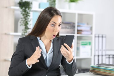 Ofisteki masada oturan akıllı telefonu kontrol eden harika bir yönetici kadın.