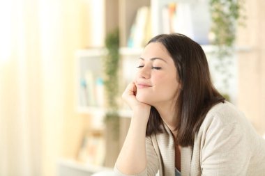 Tatmin olmuş bir kadın evdeki oturma odasında bir koltukta oturup rahatlıyor.