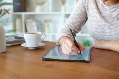 Dijital tablet üzerinde kalem kullanan bir kadının el yazısının portresini kapat