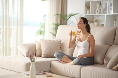 Yogi, yoga egzersizlerinden sonra ev içi bir kanepede oturarak çay kokusu alıyor.