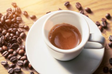 Espresso shot ahşap masa üzerinde kahve çekirdekleri ile dekore edilmiştir. Beyaz Kupası.