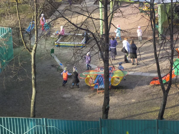 Kora tavasszal. Süt a nap. A gyerekek az udvaron játszanak. Óvoda — Stock Fotó
