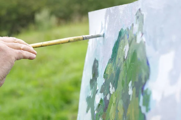 Drawing oil paintings of a natural landscape on a white cardboard