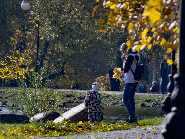 Femme avec un enfant. Automne, automne dans la ville, paysage d'automne urbain avec un étang, les gens qui marchent et d'autres amusements — Photo