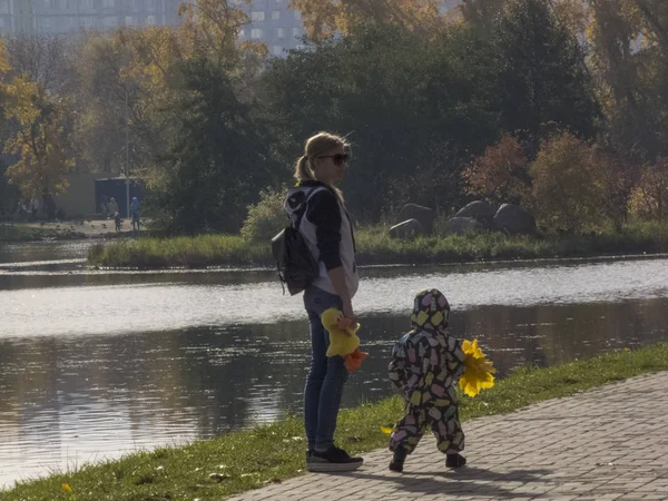 Γυναίκα με παιδί. Φθινοπωρινός χρόνος, φθινόπωρο στην πόλη, αστικό φθινοπωρινό τοπίο με λιμνούλα, άνθρωποι που περπατούν και άλλες διασκεδαστικές — Φωτογραφία Αρχείου