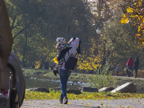 Женщина с ребенком. Осеннее время, осень в городе, городской осенний пейзаж с прудом, люди гуляют и другие развлечения — стоковое фото