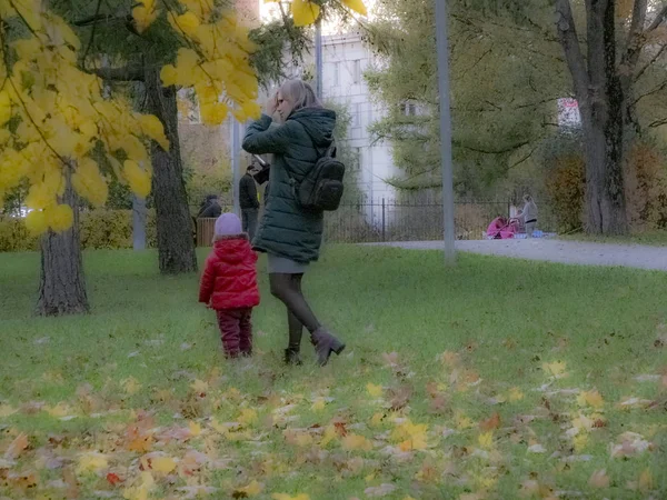 Женщина с ребенком. Маленькая девочка гуляет в осеннем парке. Осеннее время, осень в городе, городской осенний пейзаж, люди ходят пешком и другие развлечения — стоковое фото