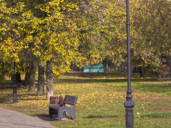 En bänk vid dammen i parken, solen skiner, och dess höst — Stockfoto