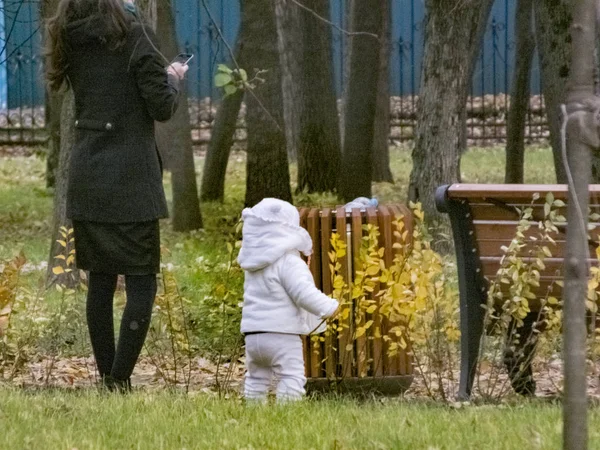 Μια γυναίκα με ένα παιδί στο πάρκο περπατάει. Είναι φθινόπωρο. — Φωτογραφία Αρχείου
