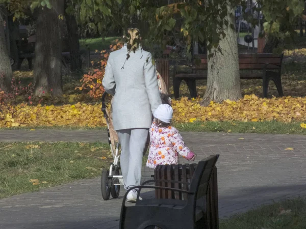 Μια γυναίκα με ένα παιδί στο πάρκο περπατάει. Είναι φθινόπωρο. — Φωτογραφία Αρχείου