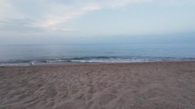 Şafak vakti kumlu sahilde dalgalar dalgalanır