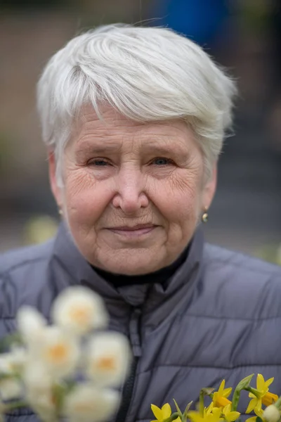 Äldre Kvinna Med Gula Blommor Bär Vinterkläder — Stockfoto