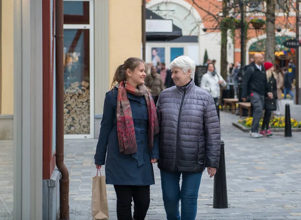 two woman, young and elderly walking on shopping street