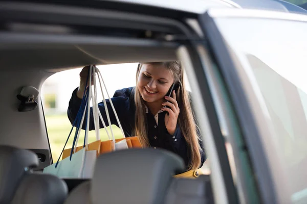 Young Woman Puts Shopping Bags Car Talks Phone — Stock Photo, Image
