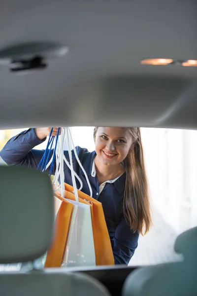 若い女性が車に買い物袋を置く — ストック写真