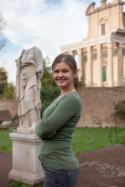 Genç kadın giyiyor yeşil kazak antika Romen bina ve Foro Romano, Rom, İtalya, heykel önünde gülümseyen