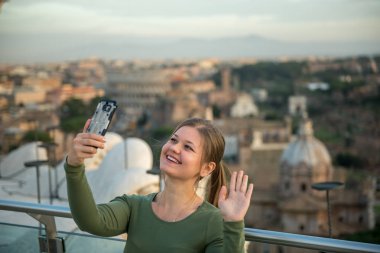 Kolezyum, Roma, İtalya, önünde çatıda yeşil kazak giyen genç kadın onun smartphone ile selfie yapar