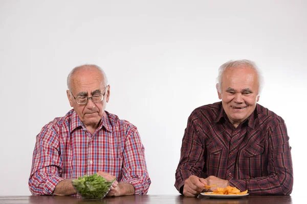 两个拿着绿色沙拉和薯片的老年男子 — 图库照片