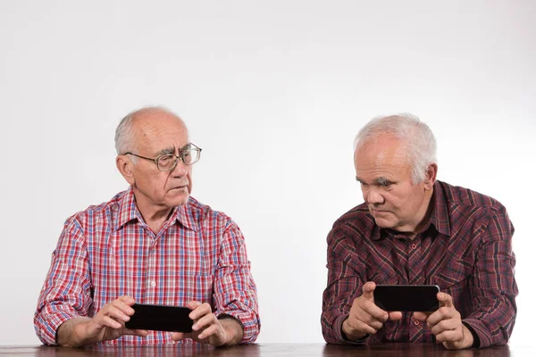 two elderly men with smart phones, playing games