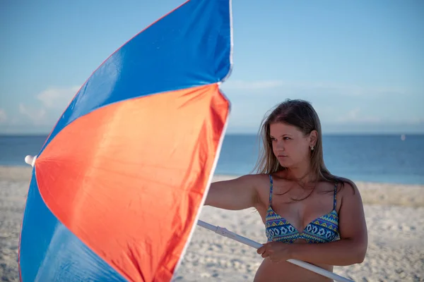 Junge Frau mit Sonnenschirm am Strand — Stockfoto