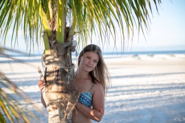 Palmiye ağacının arkasındaki bikinili genç kız