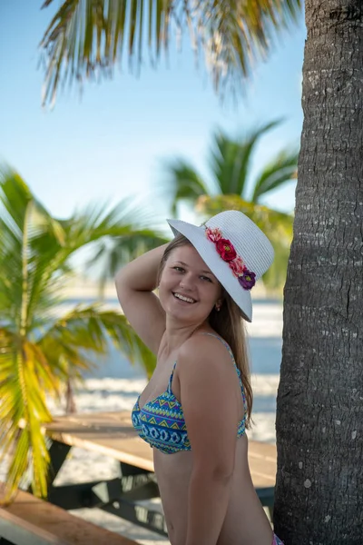 Junge Frau posiert mit Hut gegen Seeblick-Palme — Stockfoto