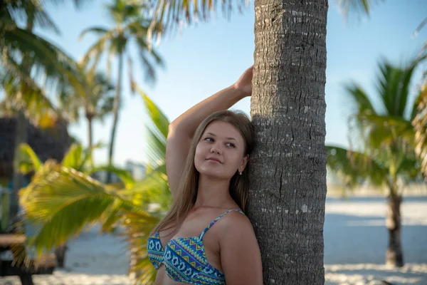 Young girl in bikini beside the palm tree — Stock Photo, Image