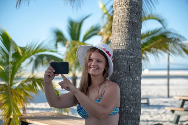 Mujer joven con smartphone delante de la palma — Foto de Stock