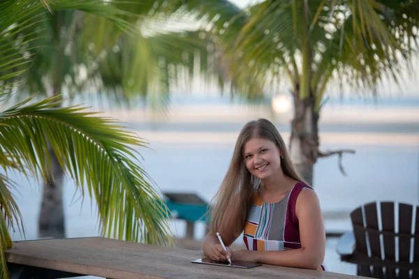 Jonge vrouw met tablet op het strand — Stockfoto