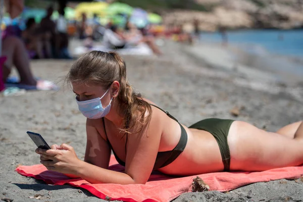 Молодая Женщина Маске Лица Переписываясь Телефону Пляже — стоковое фото