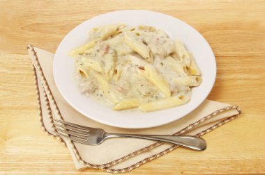 Bir tabloda bir çatal ve peçete ile makarna Fırında tavuk ve domuz pastırması