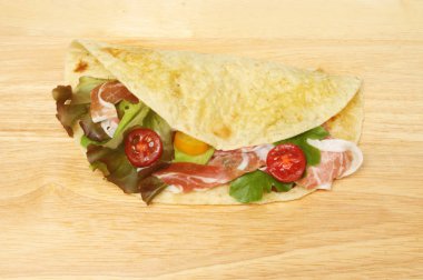 Piada gözleme salata ile dolu ve parma ham ahşap doğrama üzerinde kurulu