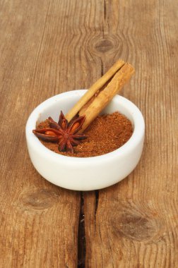 Bir ramekin Yıldız anason ve eski yıpranmış ahşap üzerine tarçın ile Çince beş baharat