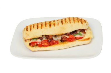 Domates, pancetta, fesleğen ve erimiş peynirli panini beyaza karşı izole edilmiş bir tabakta.