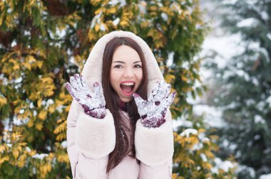 Aşağı kapüşonlu ceket ve kar eldivenleri genç güzel duygusal kadın portresi Bahçe arka plan kapsamında. Karlı kış manzarası
