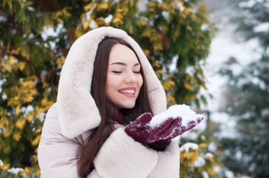Aşağı kapüşonlu ceket ve kar eldivenleri genç güzel duygusal kadın portresi Bahçe arka plan kapsamında. Karlı kış manzarası