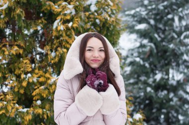 Aşağı kapüşonlu ceket ve kar eldivenleri genç güzel duygusal kadın portresi Bahçe arka plan kapsamında. Karlı kış manzarası