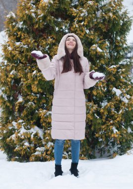 Aşağı kapüşonlu ceket ve kar eldivenleri genç güzel duygusal kadın portresi Bahçe arka plan kapsamında. Karlı kış manzarası