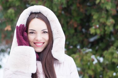 Aşağı kapüşonlu ceket ve kar eldivenleri genç güzel duygusal kadın portresi Bahçe arka plan kapsamında. Karlı kış manzarası