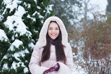 Aşağı kapüşonlu ceket ve kar eldivenleri genç güzel duygusal kadın portresi Bahçe arka plan kapsamında. Karlı kış manzarası