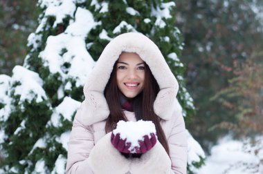 Aşağı kapüşonlu ceket ve kar eldivenleri genç güzel duygusal kadın portresi Bahçe arka plan kapsamında. Karlı kış manzarası