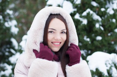 Aşağı kapüşonlu ceket ve kar eldivenleri genç güzel duygusal kadın portresi Bahçe arka plan kapsamında. Karlı kış manzarası