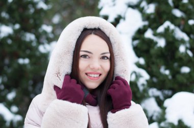 Aşağı kapüşonlu ceket ve kar eldivenleri genç güzel duygusal kadın portresi Bahçe arka plan kapsamında. Karlı kış manzarası