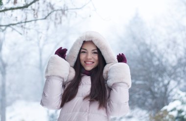 Aşağı kapüşonlu ceket ve kar eldivenleri genç güzel duygusal kadın portresi Bahçe arka plan kapsamında. Karlı kış manzarası