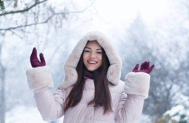 Aşağı kapüşonlu ceket ve kar eldivenleri genç güzel duygusal kadın portresi Bahçe arka plan kapsamında. Karlı kış manzarası