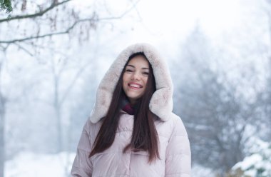 Aşağı kapüşonlu ceket ve kar eldivenleri genç güzel duygusal kadın portresi Bahçe arka plan kapsamında. Karlı kış manzarası