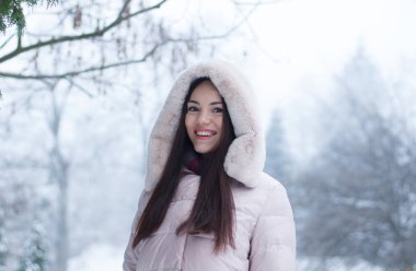 Aşağı kapüşonlu ceket ve kar eldivenleri genç güzel duygusal kadın portresi Bahçe arka plan kapsamında. Karlı kış manzarası