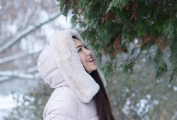 Aşağı kapüşonlu ceket ve kar eldivenleri genç güzel duygusal kadın portresi Bahçe arka plan kapsamında. Karlı kış manzarası