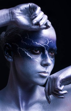 Siyah arka planda yıldırım yüzlü genç bir kadın. Kadın yıldırım tasarımı vücut sanatı. Mavi gümüş yüz sanatı.